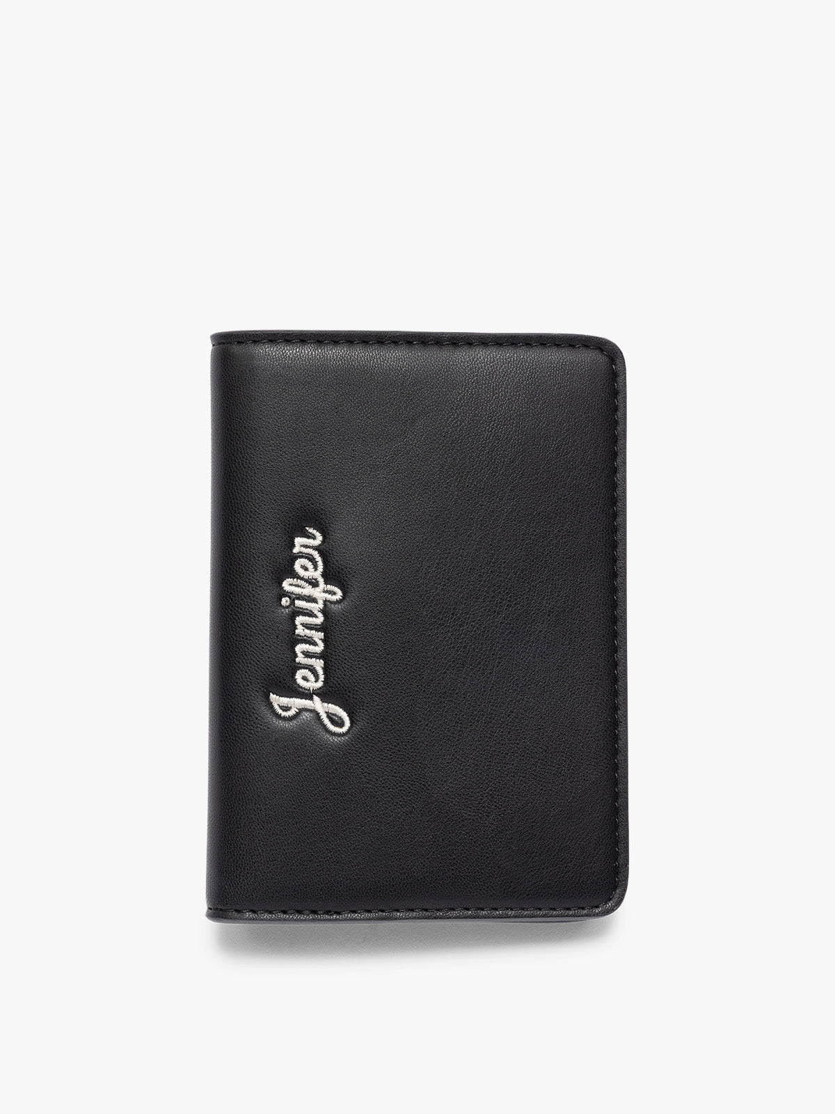 A black CALPAK Passport Holder with the brand name 'Jennifer' embossed vertically on the front, shown against a plain white background; PWTS2601-BLACK