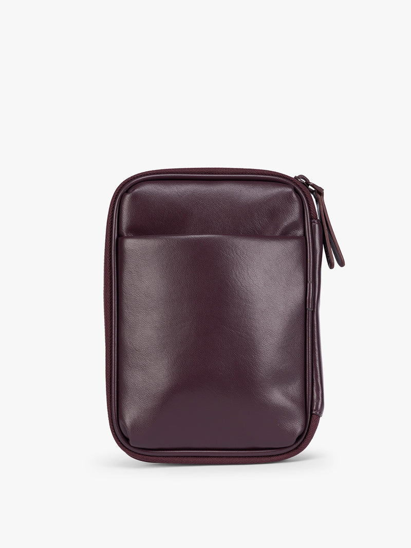 Backside of a deep burgundy Dark Cherry CALPAK Luka Zip Passport Wallet in vegan leather with a zippered top and a front pocket, shown on a plain white background