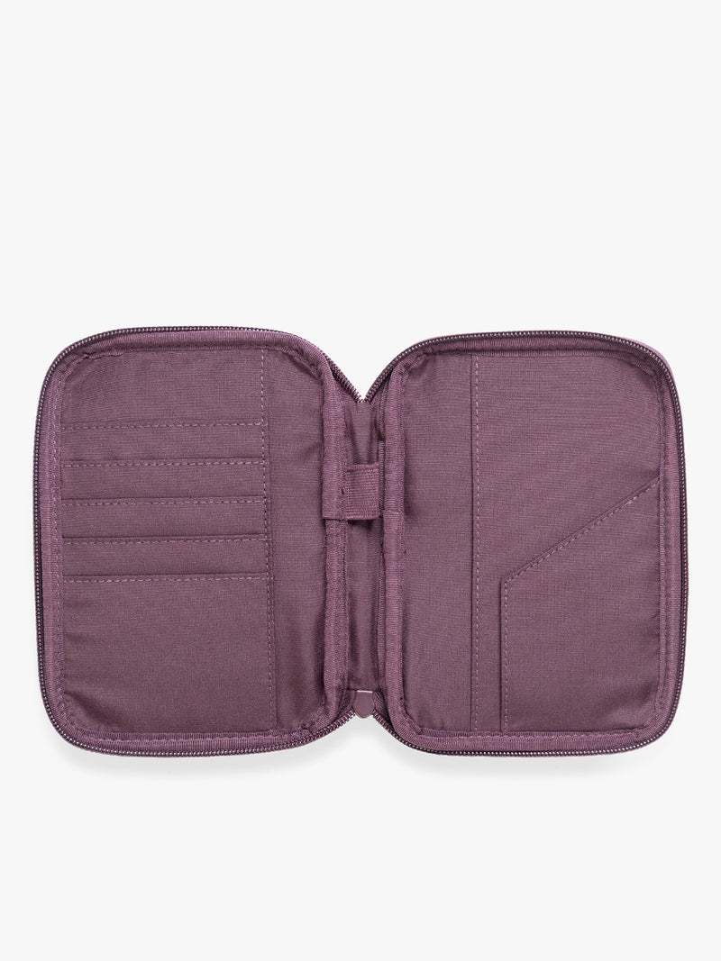 Opened view of a deep burgundy Dark Cherry CALPAK Luka Zip Passport Wallet in vegan leather with a zippered top and a front pocket, shown on a plain white background
