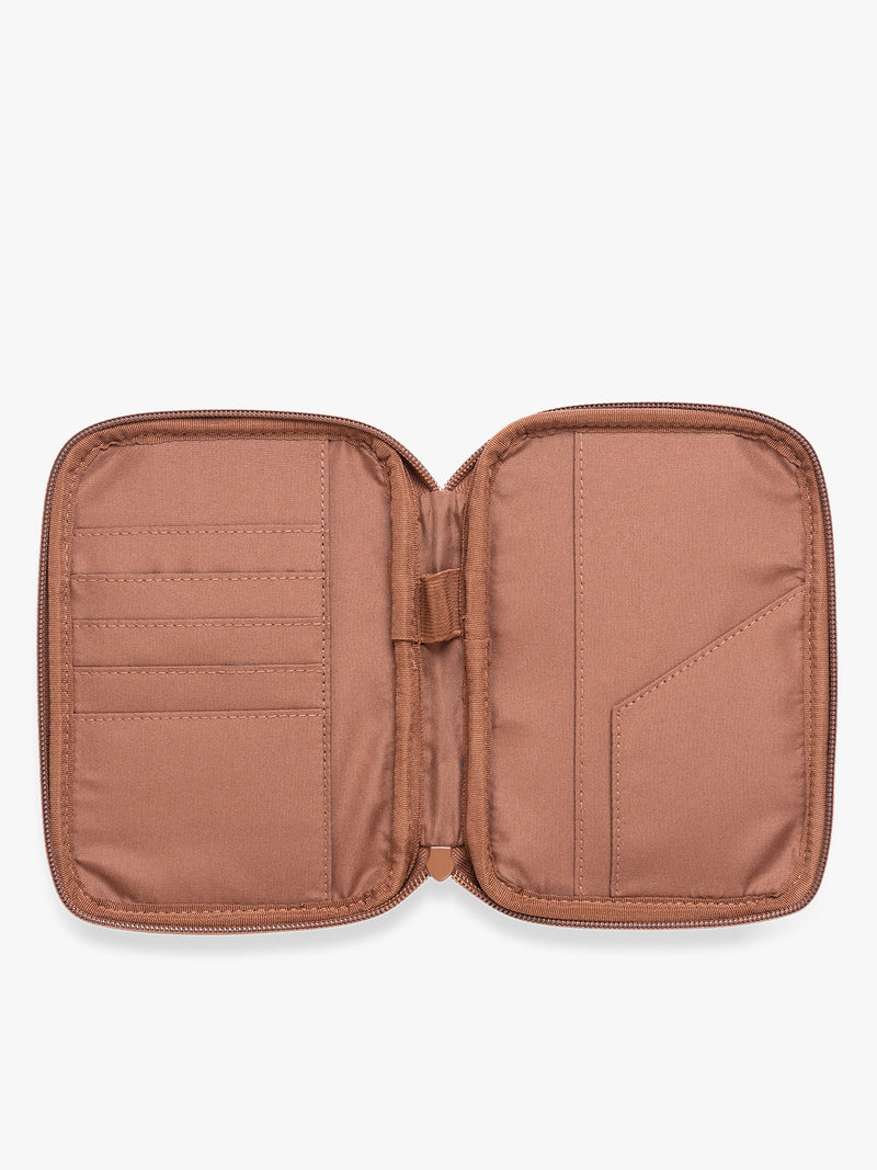 Opened view of a light Honey Brown CALPAK Luka Zip Passport Wallet in vegan leather with a zippered top and a front pocket, shown on a plain white background