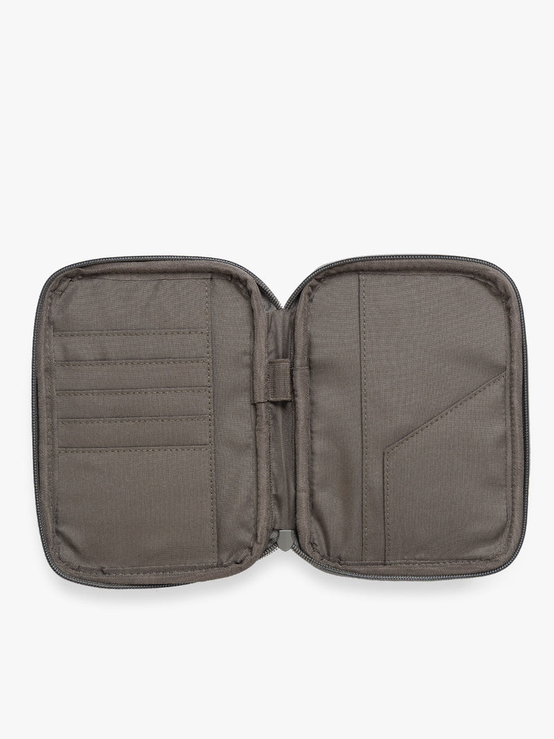 Opened view of a dark brown Mushroom CALPAK Luka Zip Passport Wallet in vegan leather with a zippered top and a front pocket, shown on a plain white background