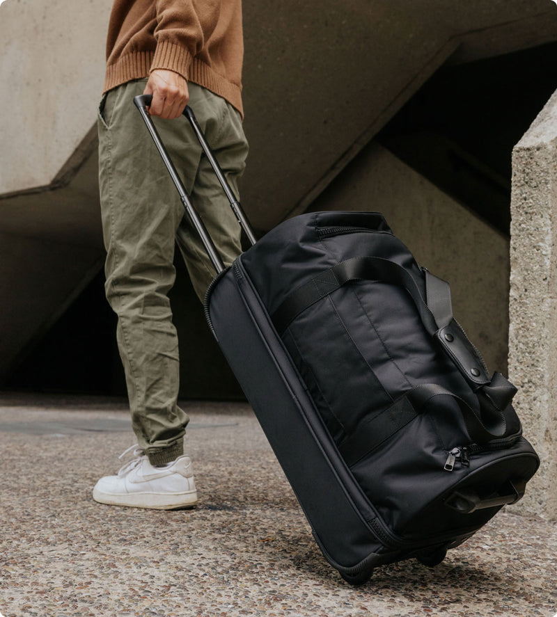 Model rolling Stevyn Large Rolling Duffel in black with 360 spinner wheels