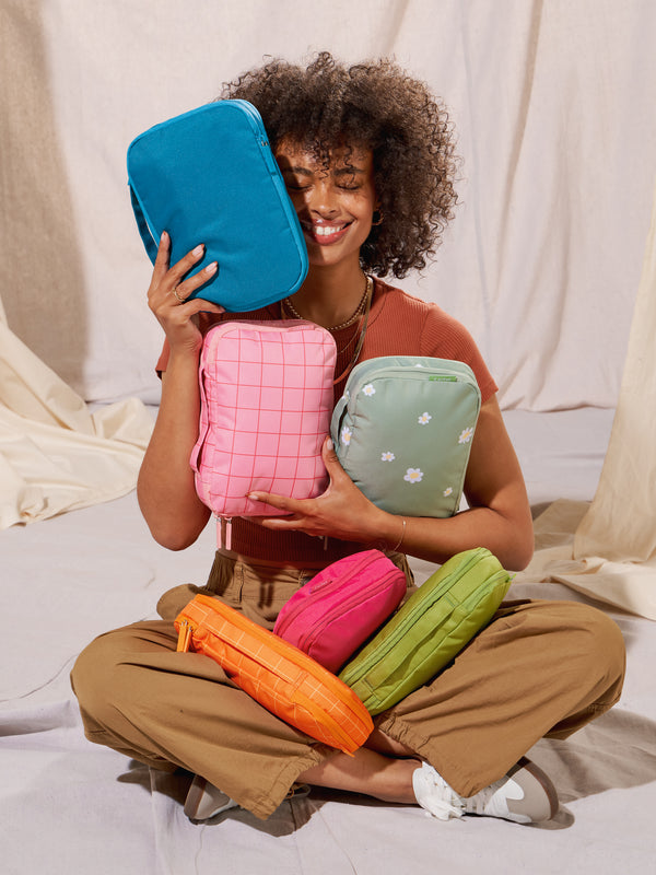 Modeling holding CALPAK small compression packing cubes with top handle in blue, pink, green and orange
