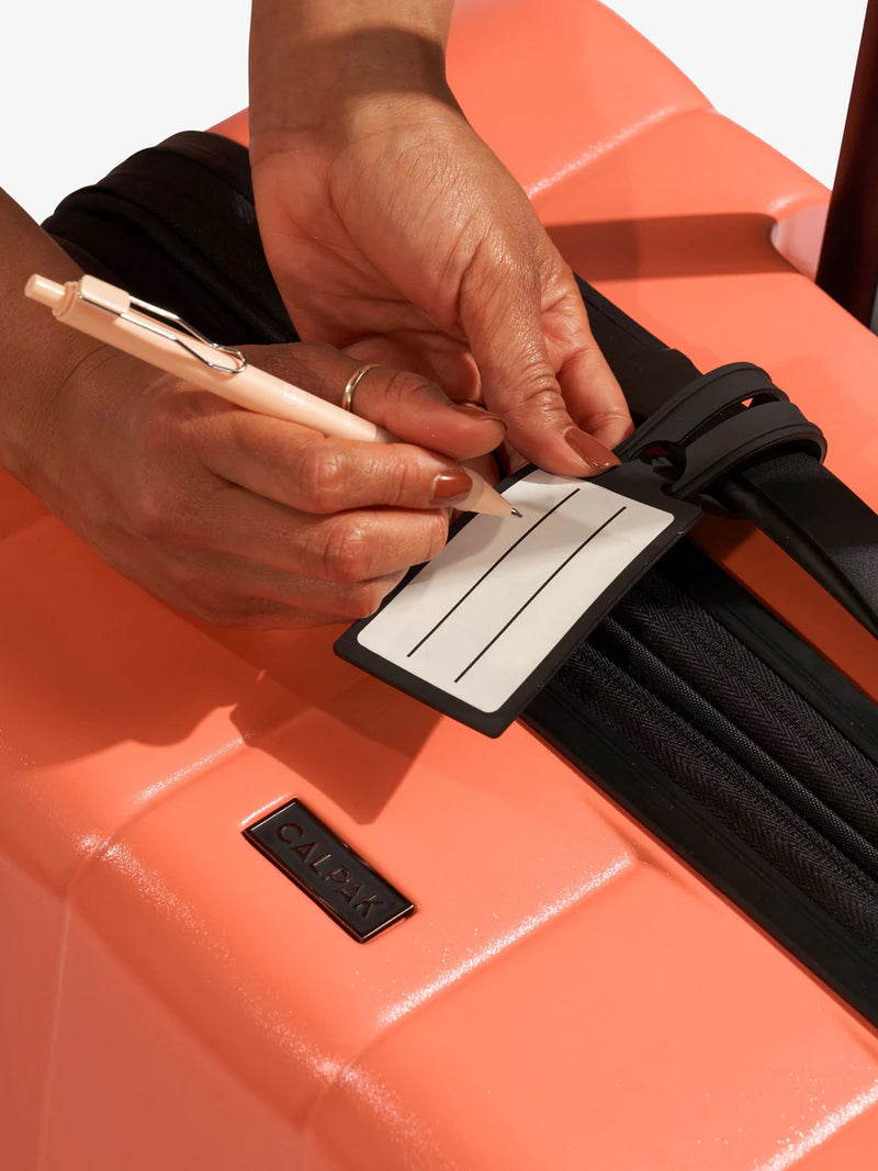 View of luggage tag attached to CALPAK Evry Starter Bundle in Persimmon