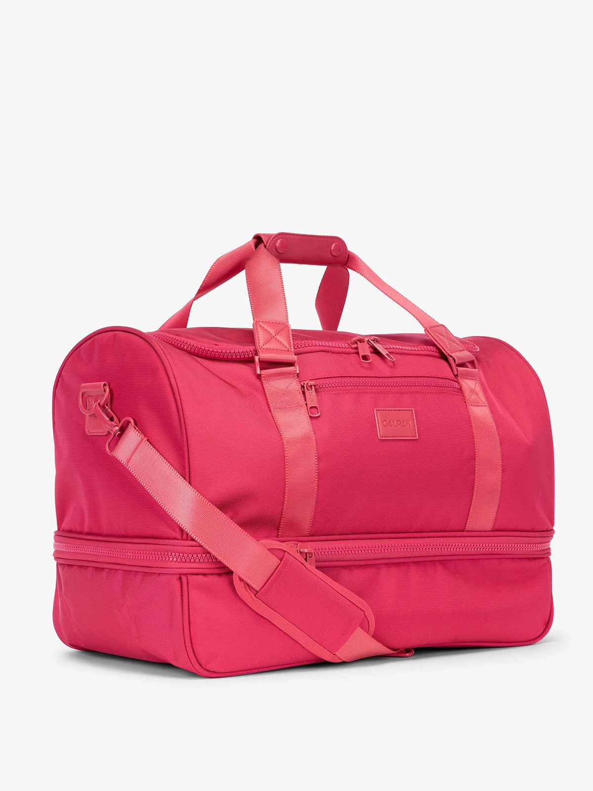 Side-view of pink dragonfruit CALPAK Stevyn Duffel with strap, carry handles, and zippered compartments