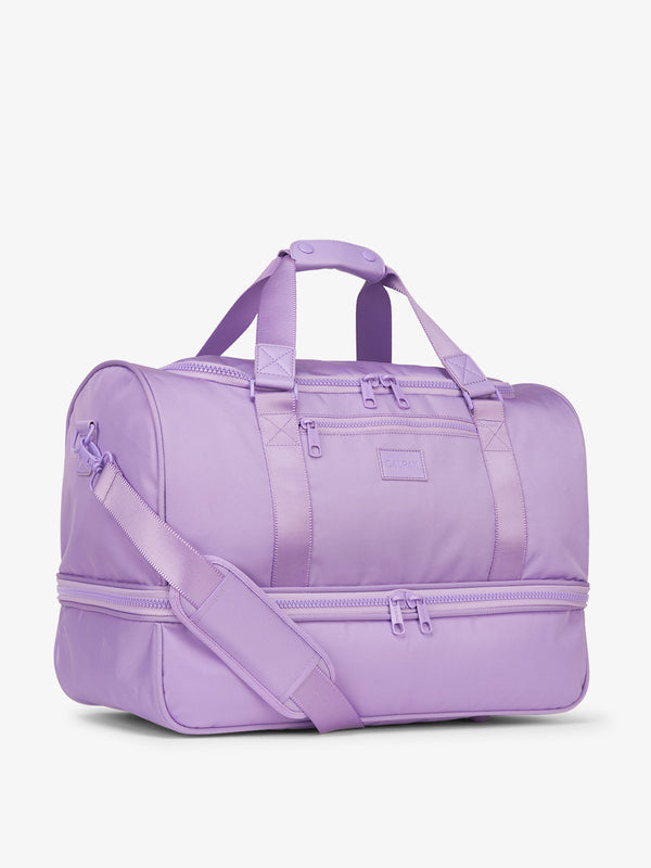 Side-view of purple orchid CALPAK Stevyn Duffel with strap, carry handles, and zippered compartments