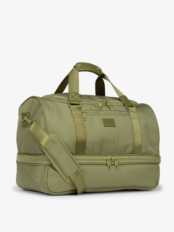 Side-view of green pistachio CALPAK Stevyn Duffel with strap, carry handles, and zippered compartments