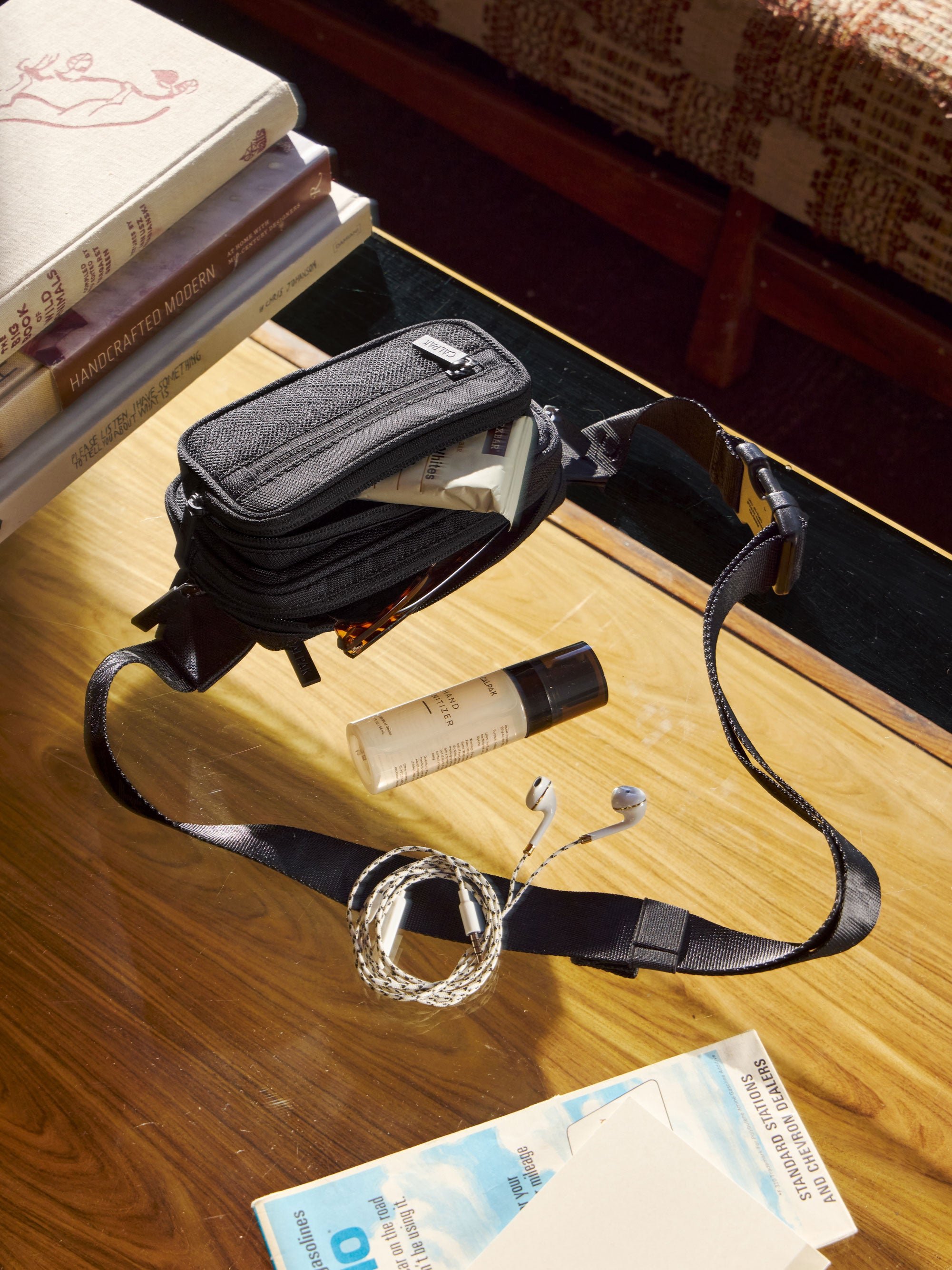 CALPAK fanny pack in black with protein bar in the front zippered pocket