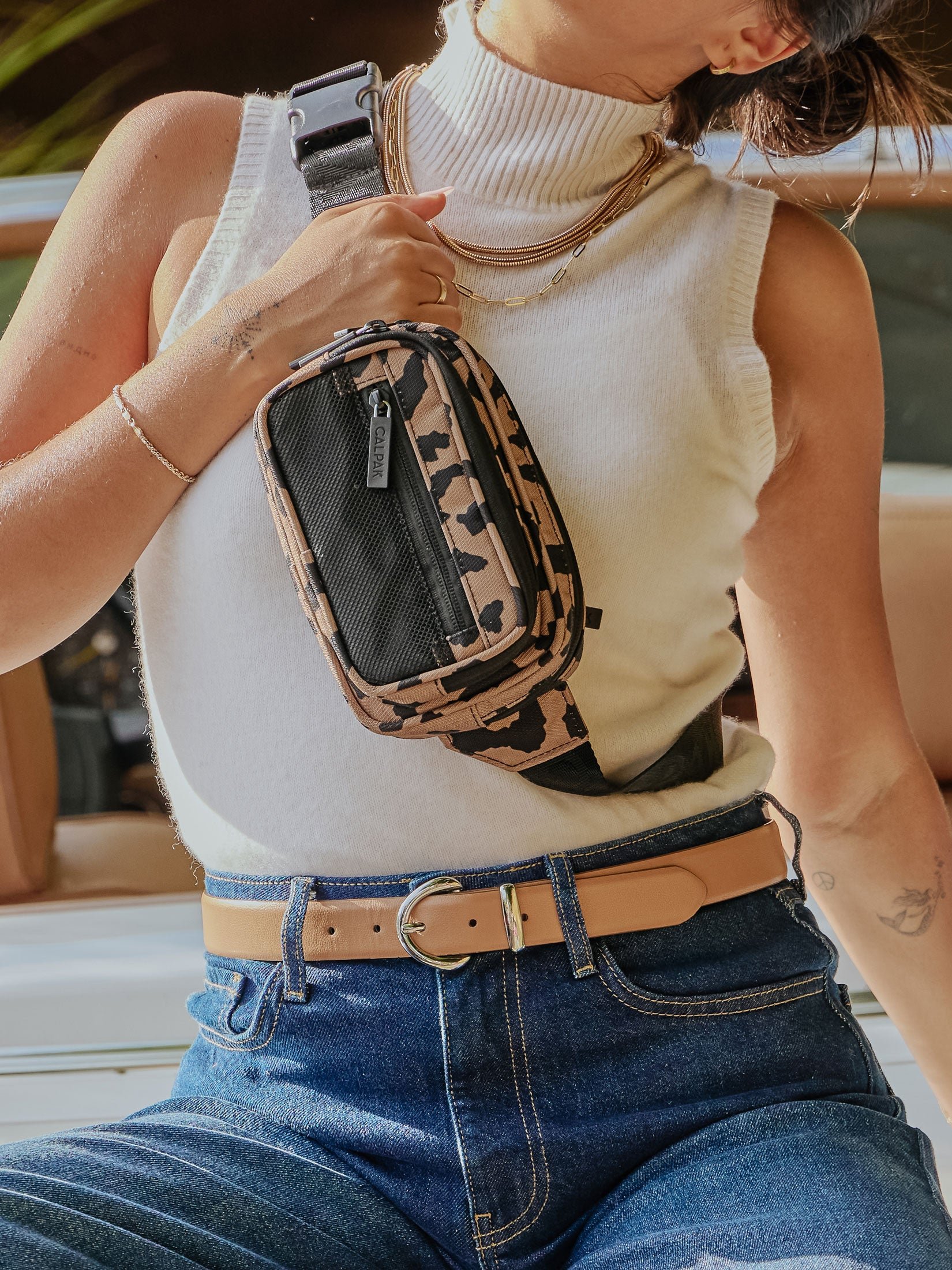 Model wearing CALPAK Stevyn Duffel as crossbody bag with adjustable strap in cheetah
