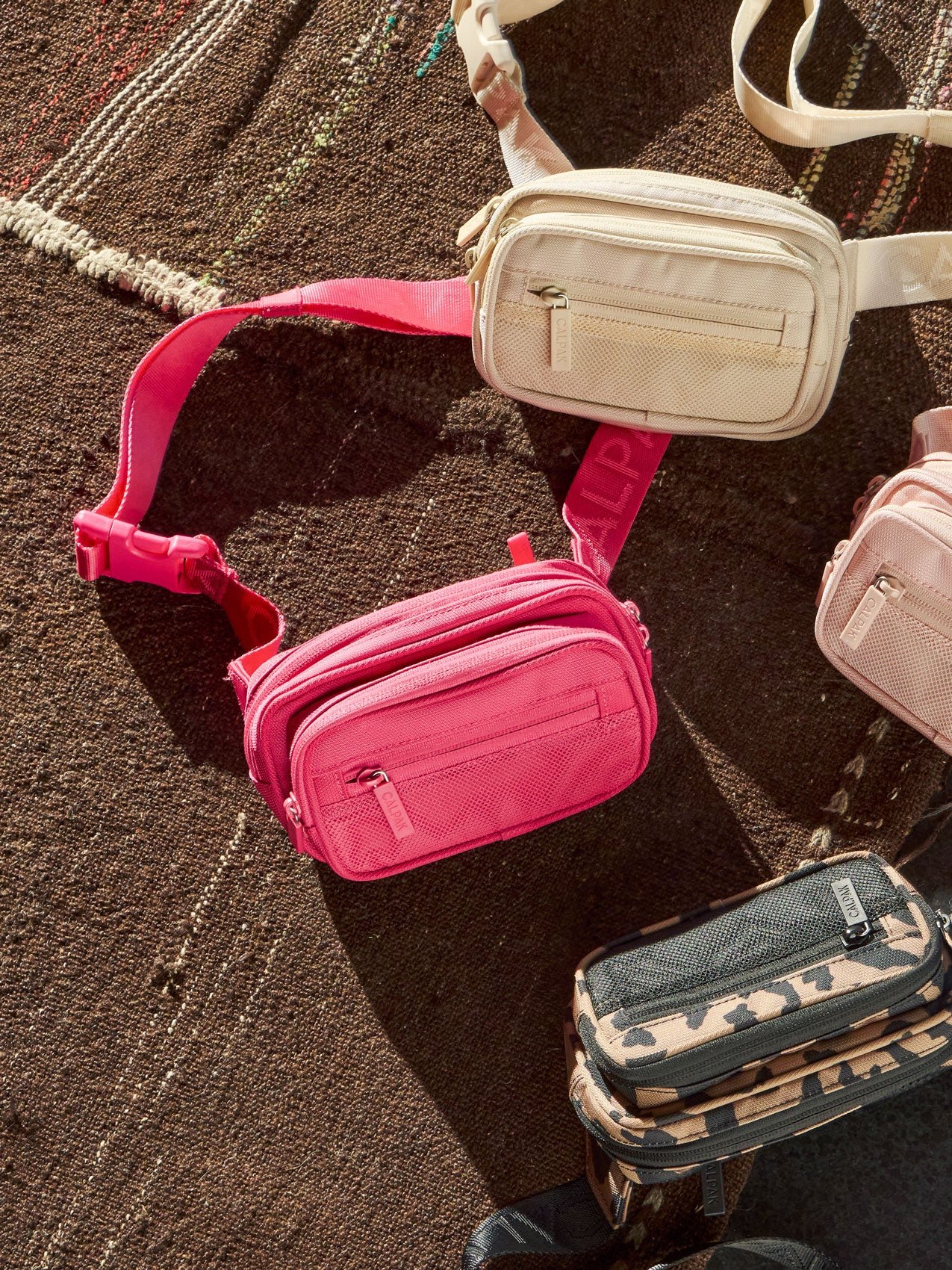 CALPAK Stevyn Fanny Packs in dragonfruit, dune, pink sand, and cheetah