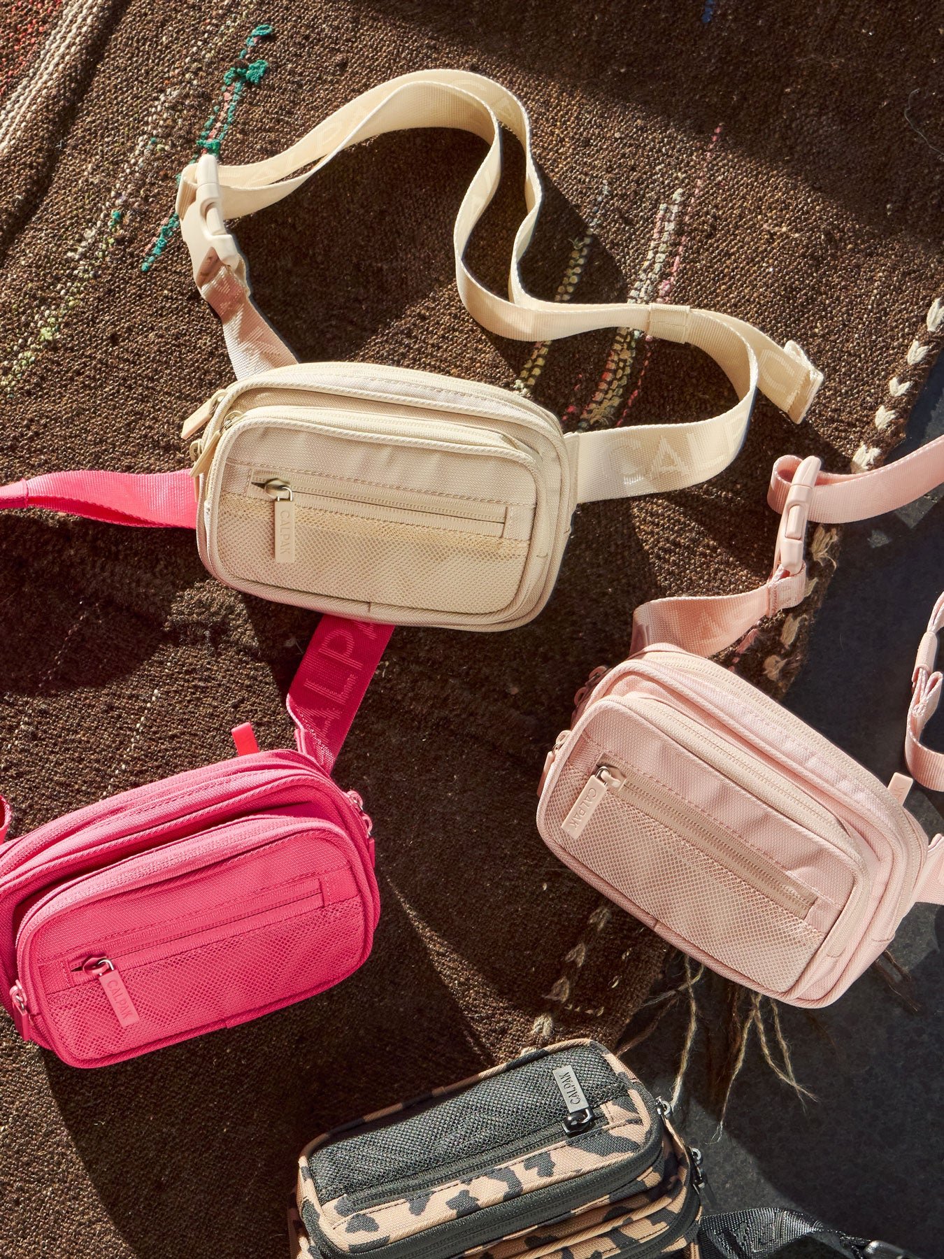 CALPAK Stevyn Fanny Packs in dune, dragonfruit, pink sand, and cheetah