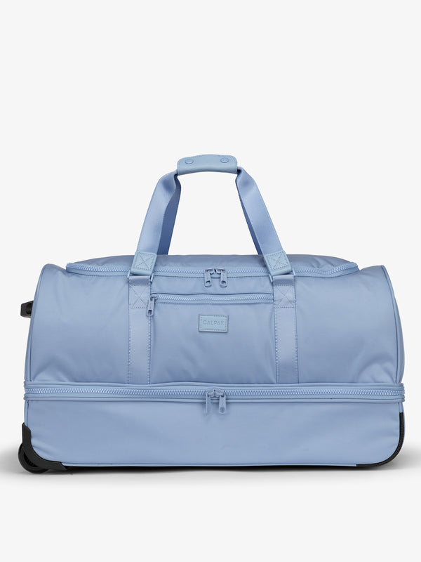 CALPAK Large Stevyn Rolling Duffel featuring dual handles, zipper enclosed compartments, and shoe compartment in sky