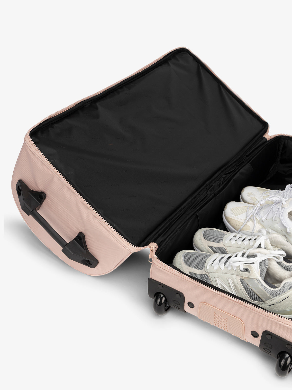 Interior of large shoe compartment in the rolling travel duffel bag in pink sand
