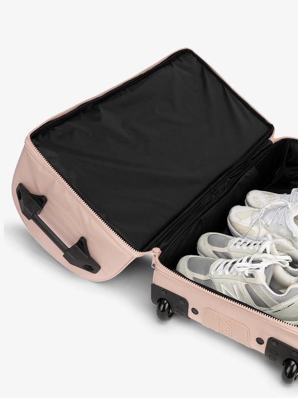 Interior of CALPAK  large shoe compartment in the rolling travel duffel bag in pink sand
