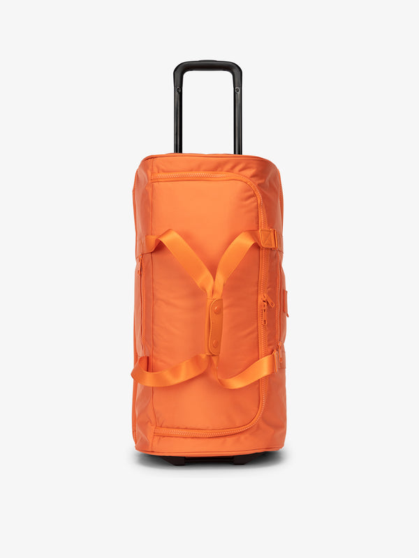 CALPAK large rolling duffel bag with wheels featuring an extended top handle in orange