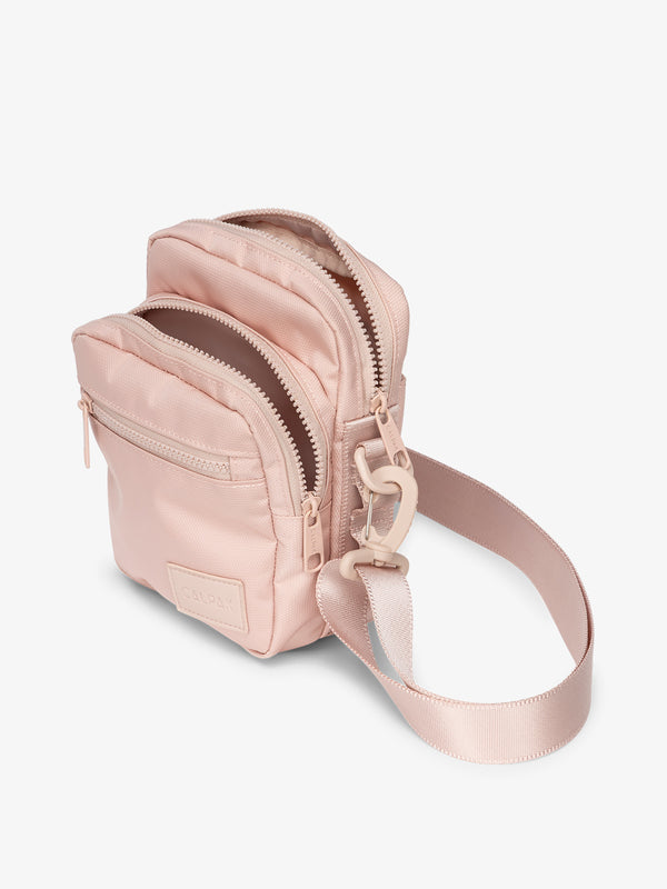 Pink CALPAK Stevyn Mini Crossbody Bag with adjustable shoulder strap, zippered pockets, and interior zipper pocket