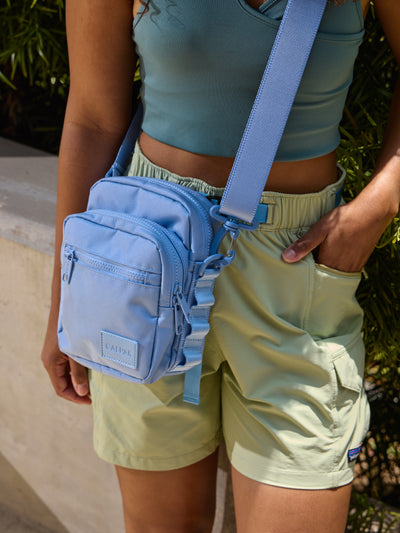 Front-view of CALPAK Stevyn Mini Crossbody Bag with zippered pockets and side panel daisy chains in sky blue; ACS2301-SKY