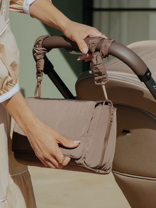 Model displaying CALPAK Stroller Straps attached to Convertible Stroller Caddy Crossbody in hazelnut