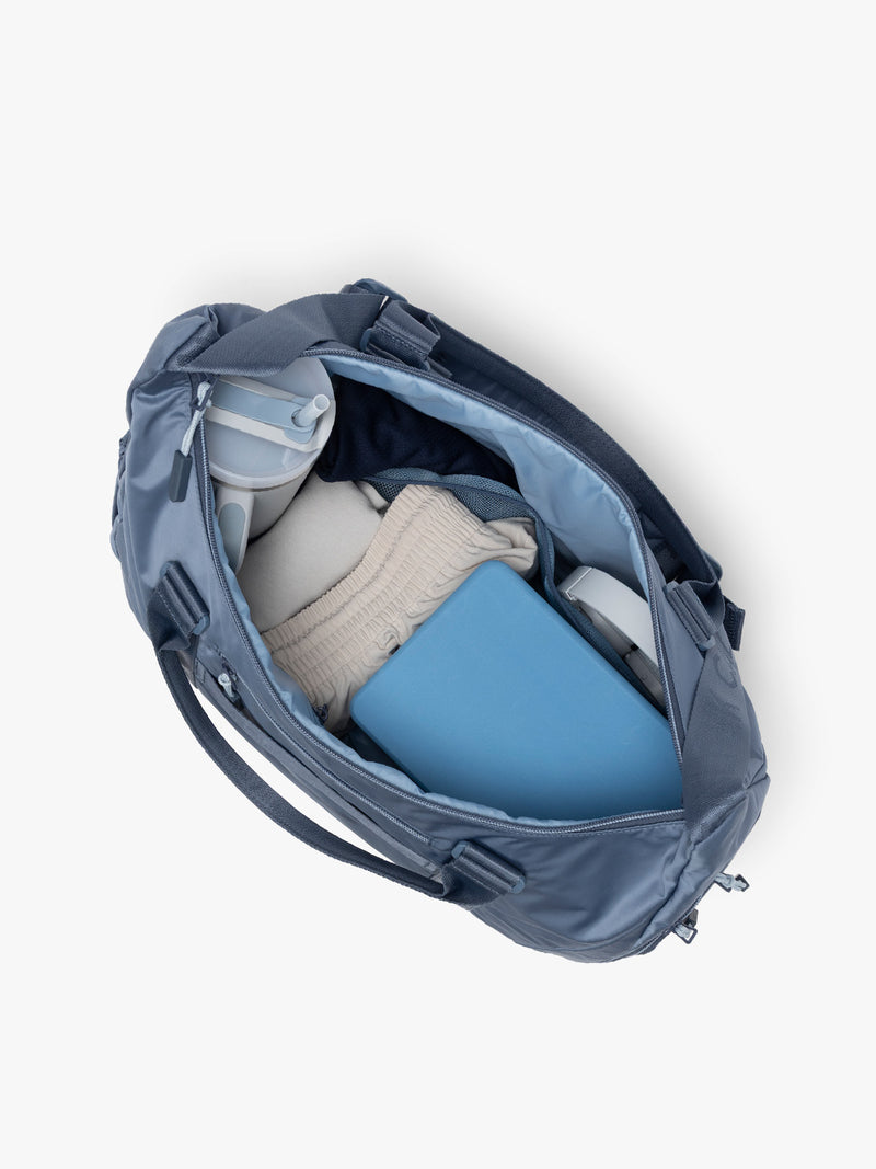 Gym Essentials in the CALPAK Fit Gym Duffel Bag in blue Indigo