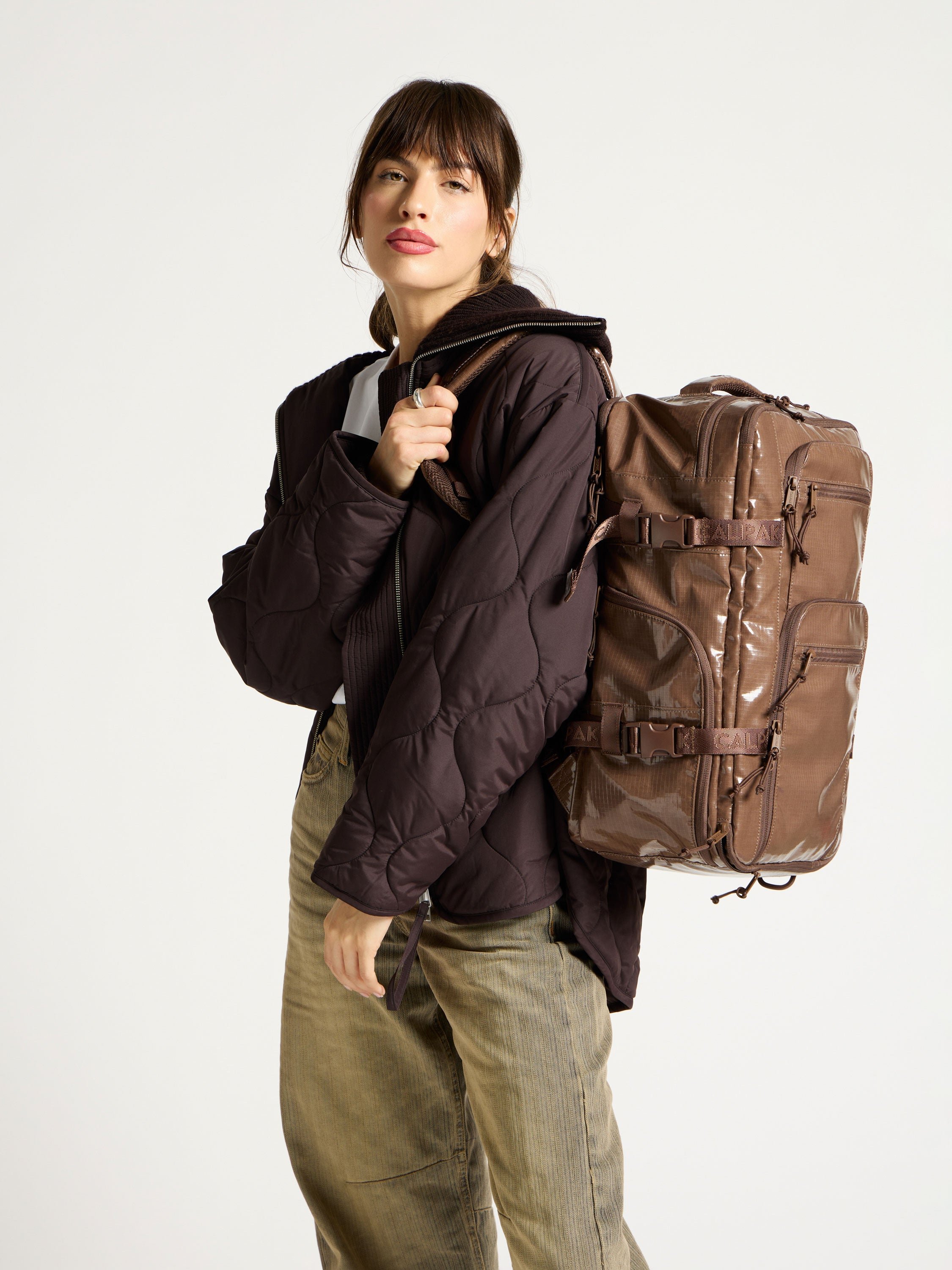 Model wearing brown CALPAK Laptop Backpack Duffel for hiking
