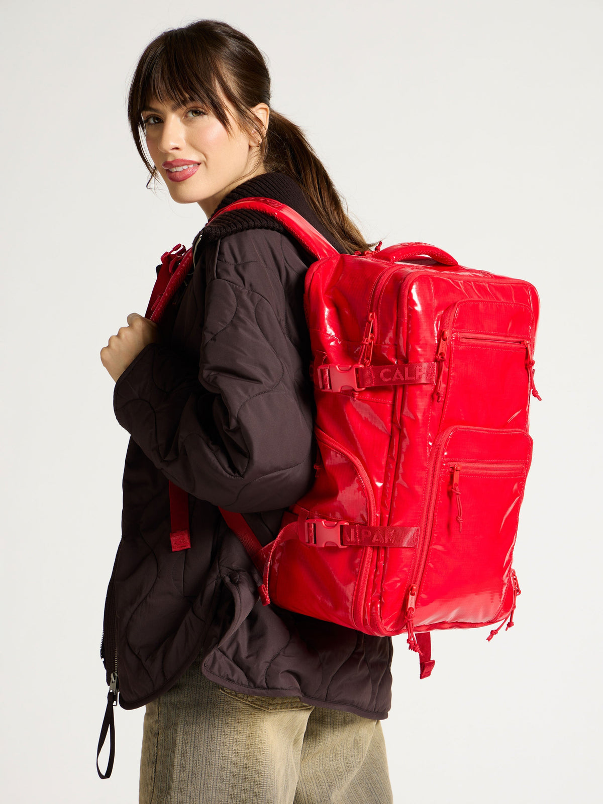 Model wearing CALPAK Terra 26L Laptop Backpack Duffel in red for hiking; BPH2201-FLAME