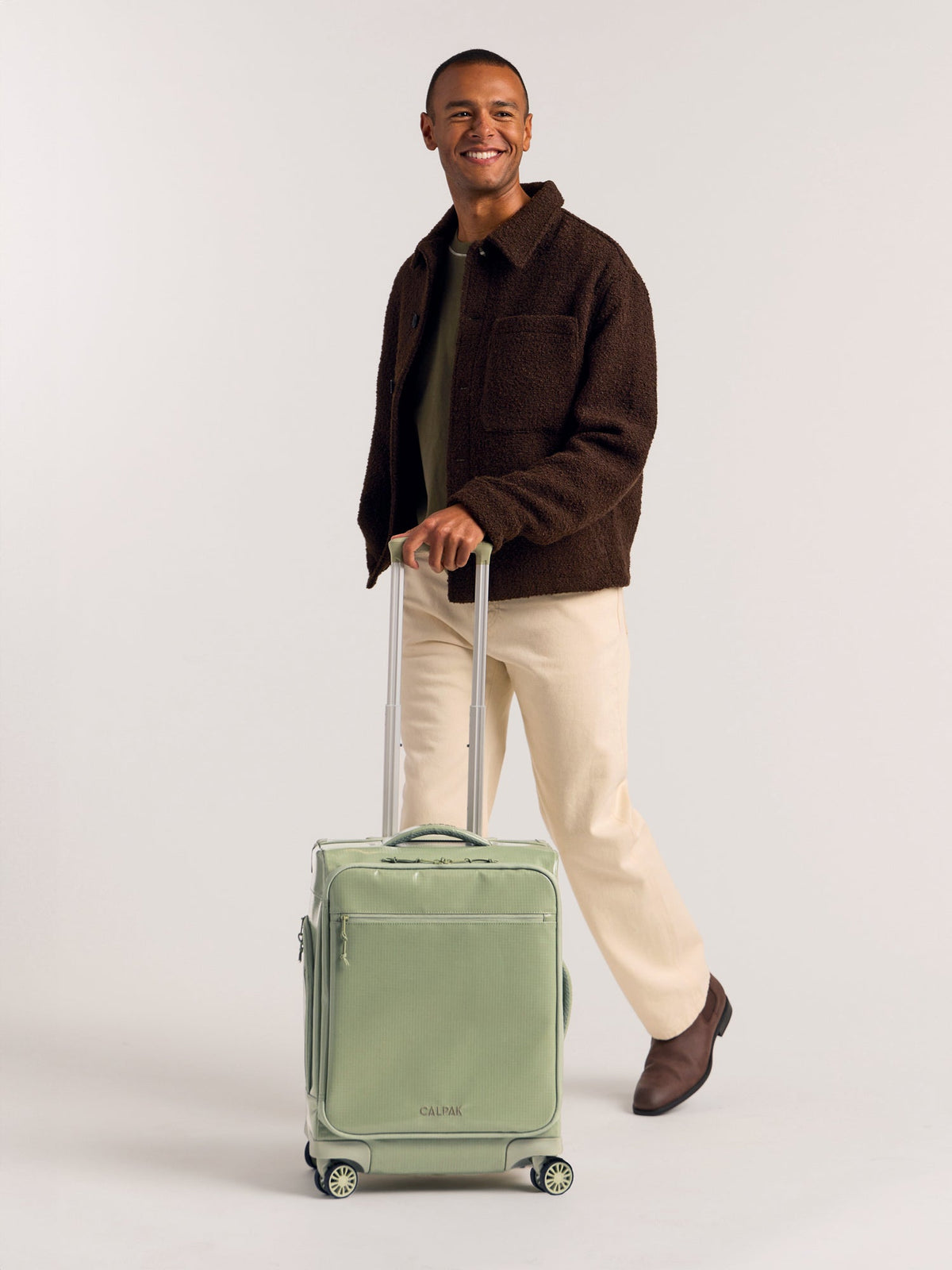 Model rolling CALPAK Terra 35L Soft Sided Carry-On Luggage in green juniper; LTR1020-JUNIPER