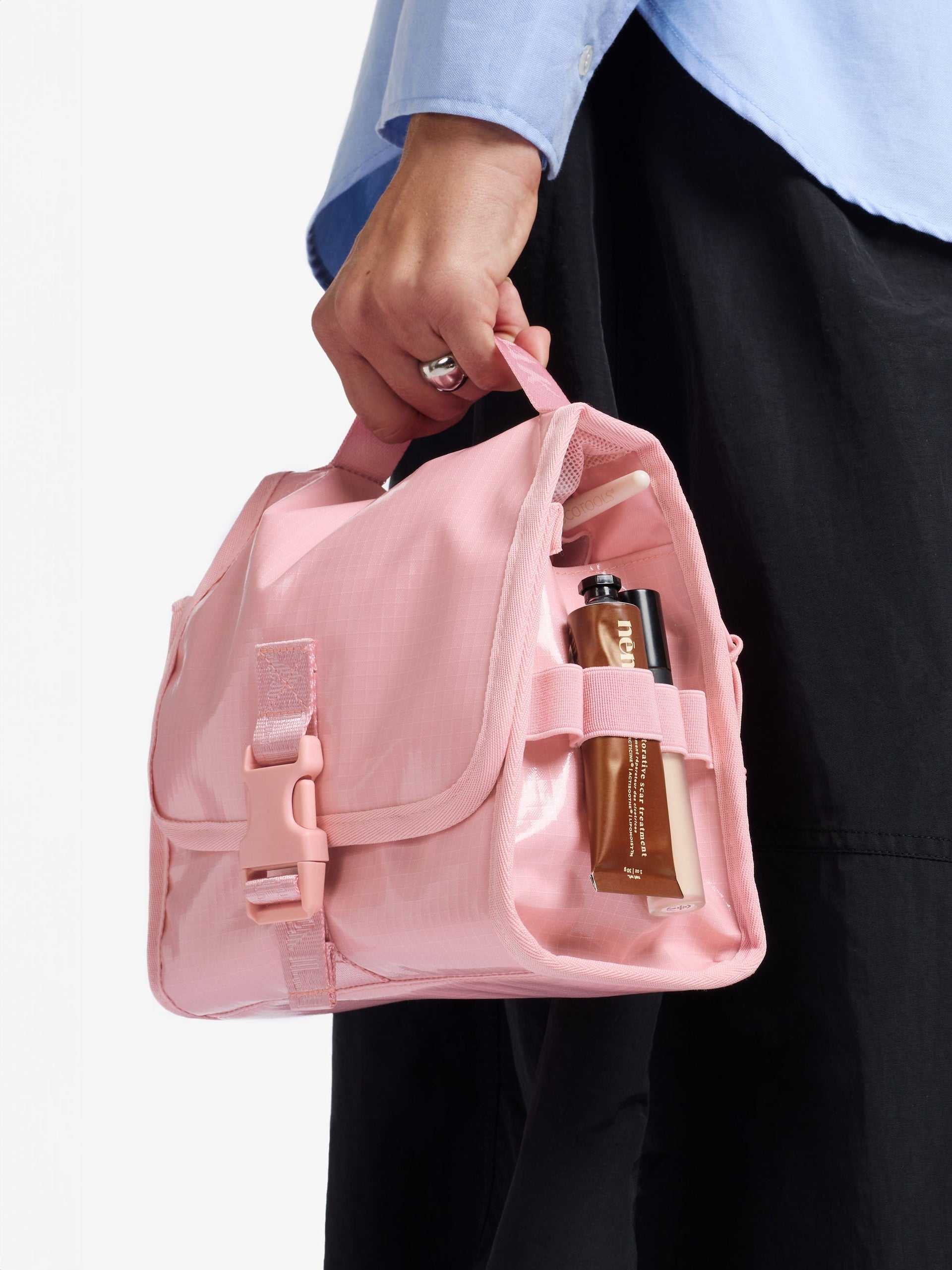 Model holding CALPAK Terra Hanging Toiletry Bag by durable carry handle with front buckle clip in pink; THY2201-BLOSSOM