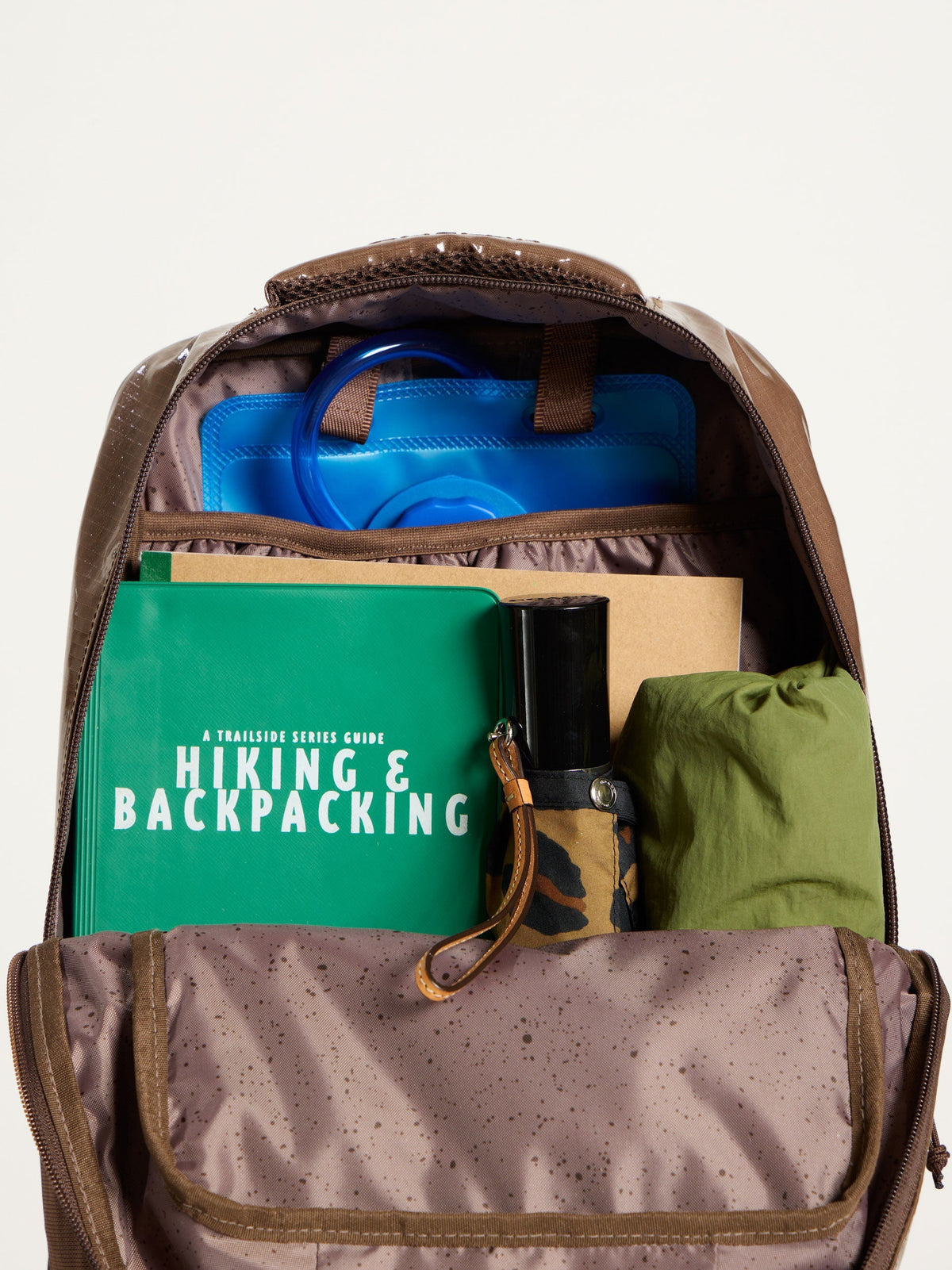 CALPAK Terra Hydration Backpack interior with items packed within and hydration reservoir in back slip pocket in cacao; BPT2201-CACAO