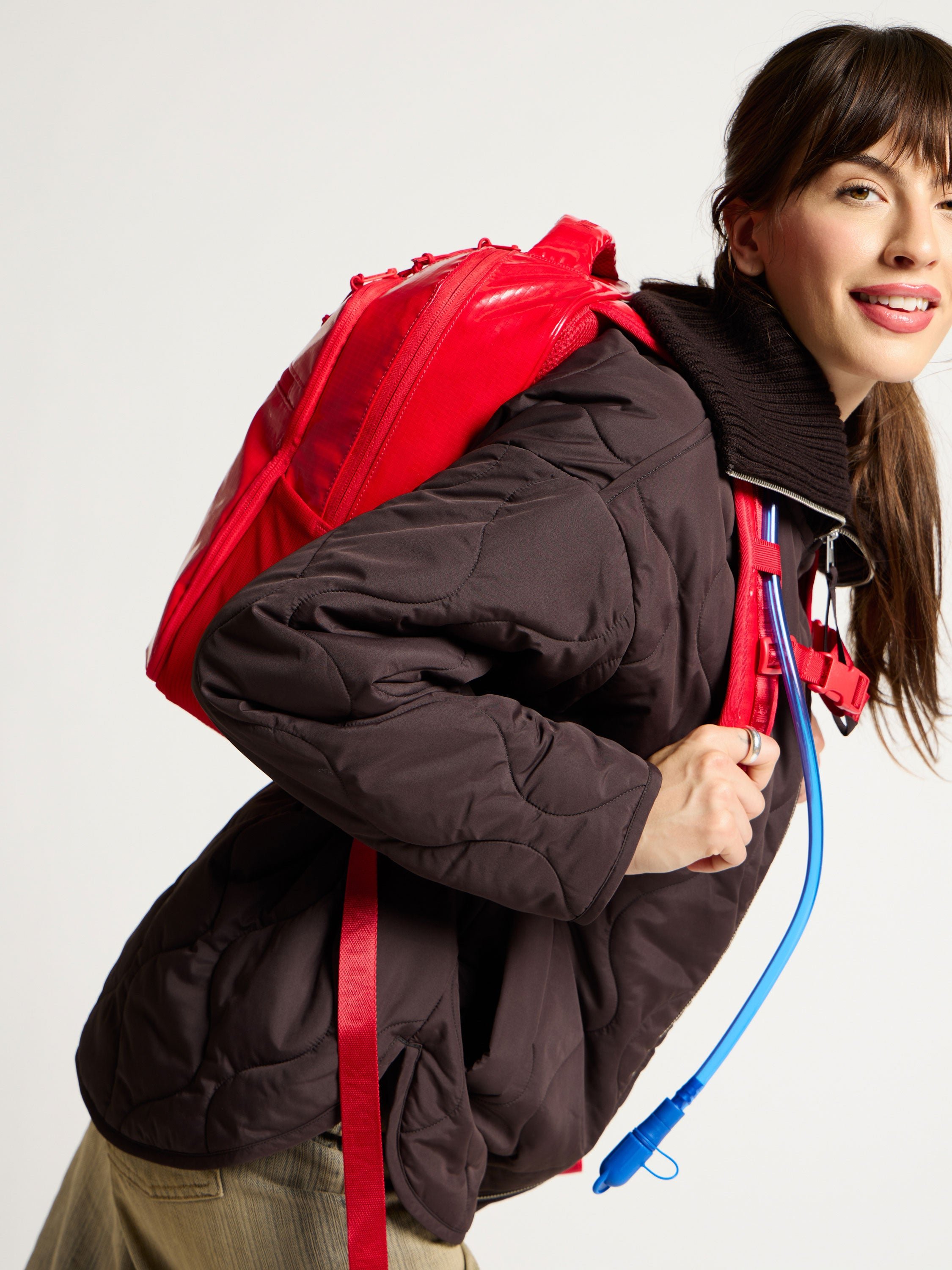 Model wearing red CALPAK Hydration Backpack on back