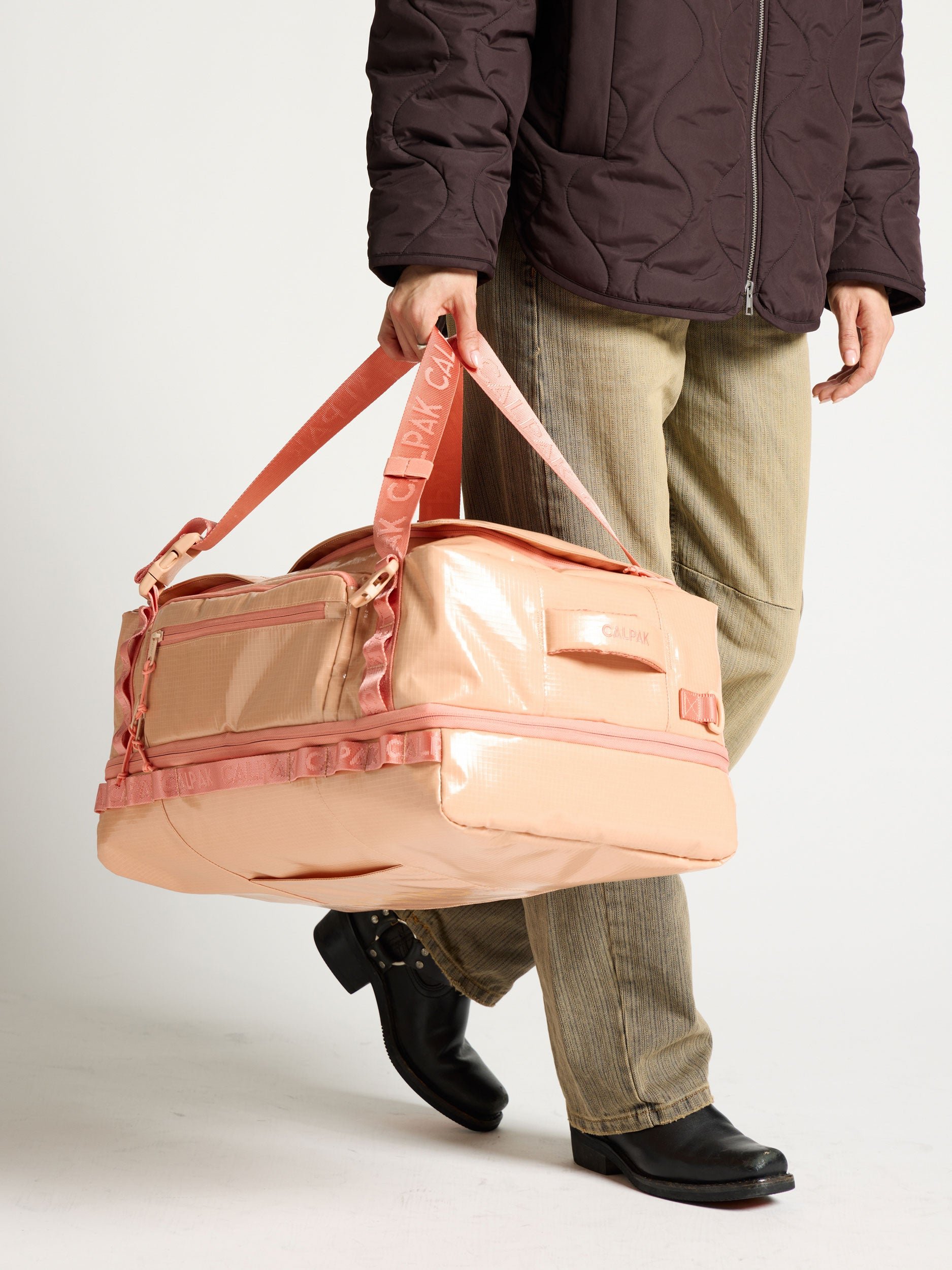 Model holding terra large 50L duffel backpack as duffel bag in orange canyon