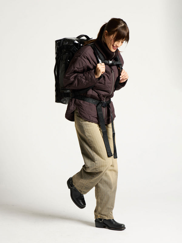 Model wearing terra large 50L duffel backpack and displaying adjustable top chest strap and bottom waist strap