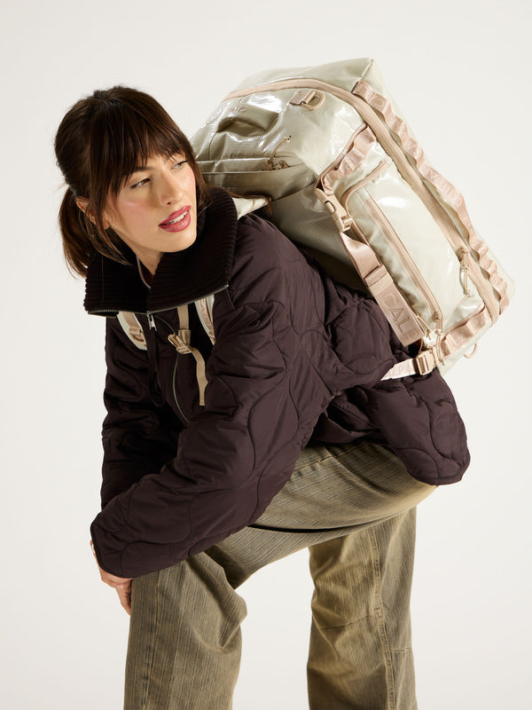 Model wearing terra large 50L duffel backpack on back with sternum strap across chest in beige