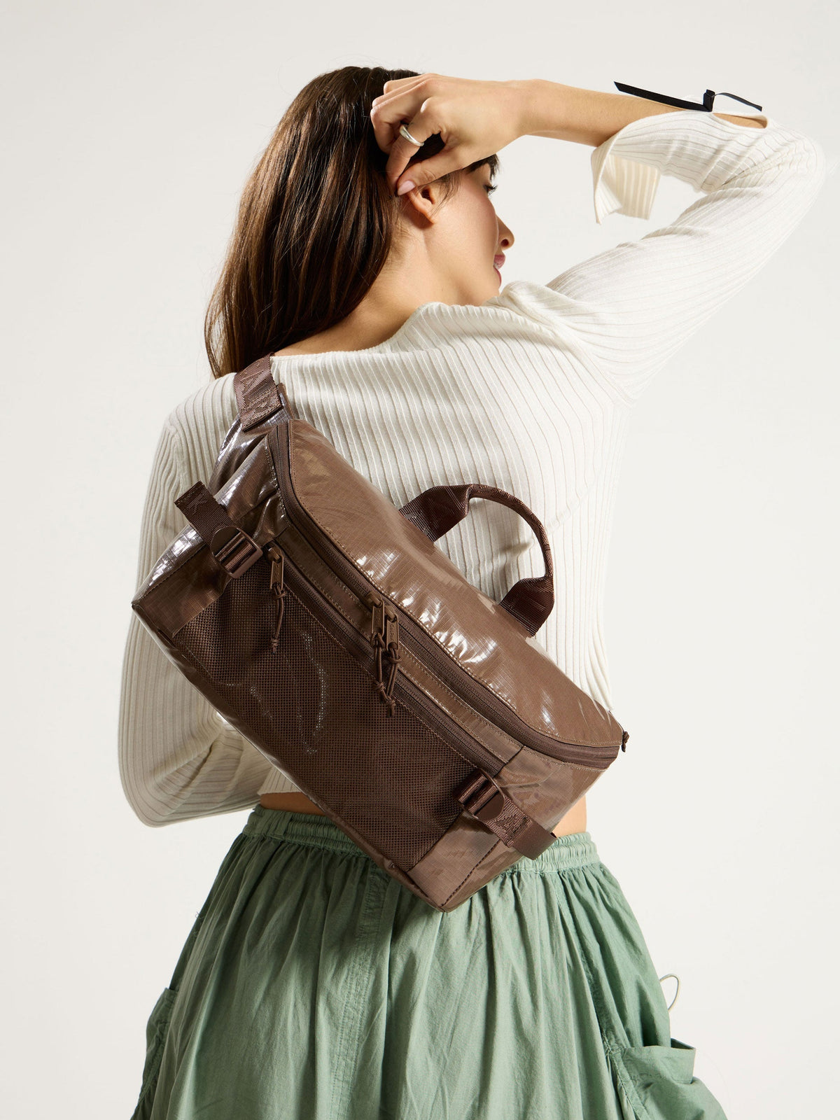 Model wearing CALPAK Terra Sling Bag in chocolate as crossbody bag; CBH2201-CACAO