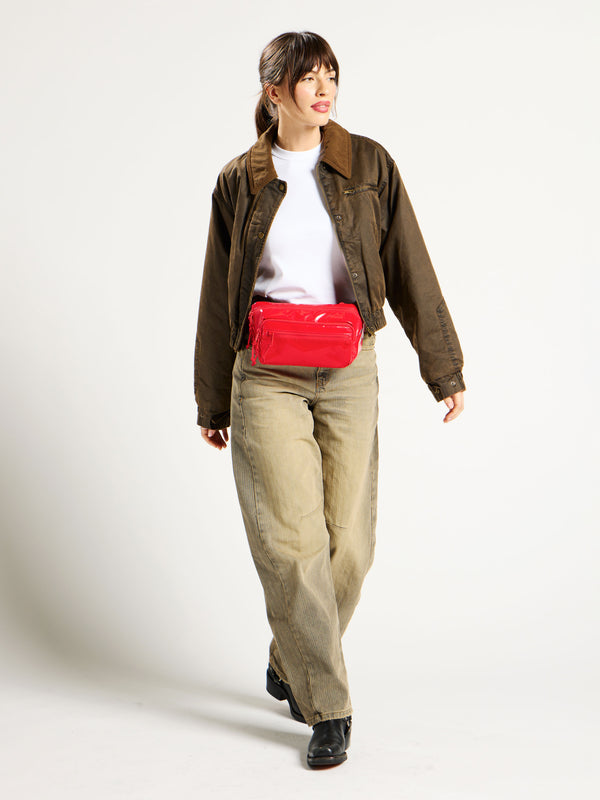 Model wearing CALPAK Terra Small Sling Bag around waist in red flame