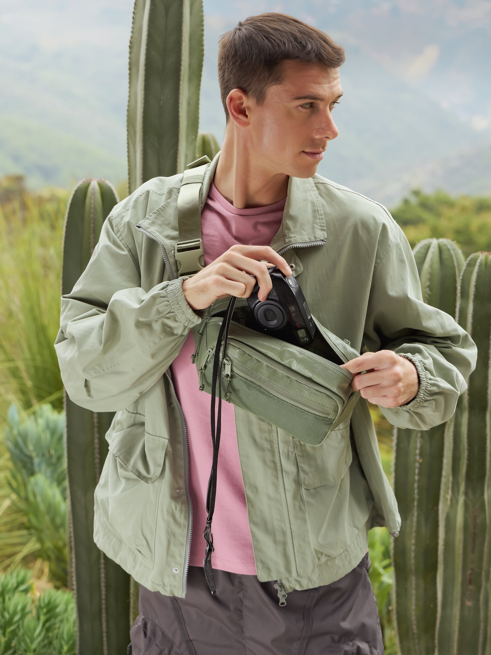 Model wearing CALPAK Terra small belt bag with adjustable strap and mesh front pocket in green; BBT2301-JUNIPER