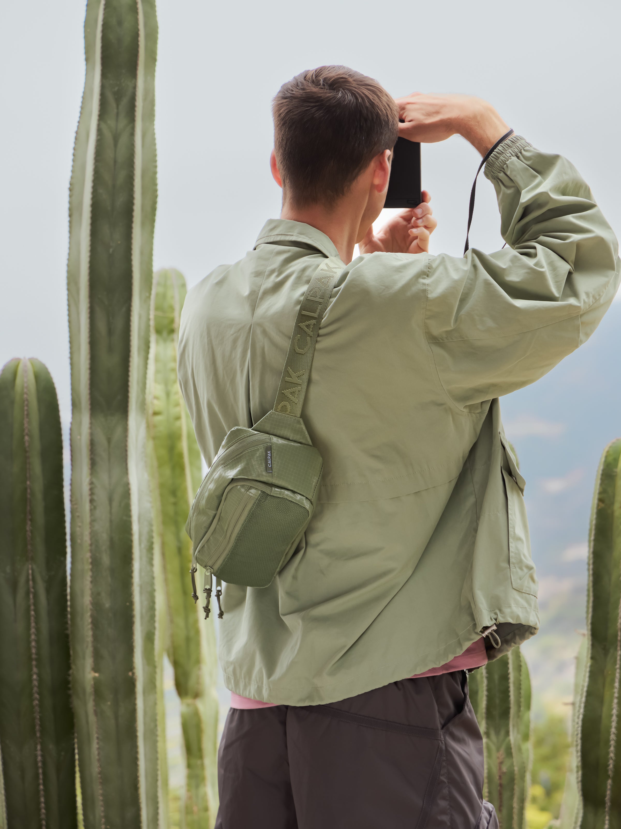 Model wearing Terra crossbody belt bag with adjustable strap and water resistant exterior in juniper