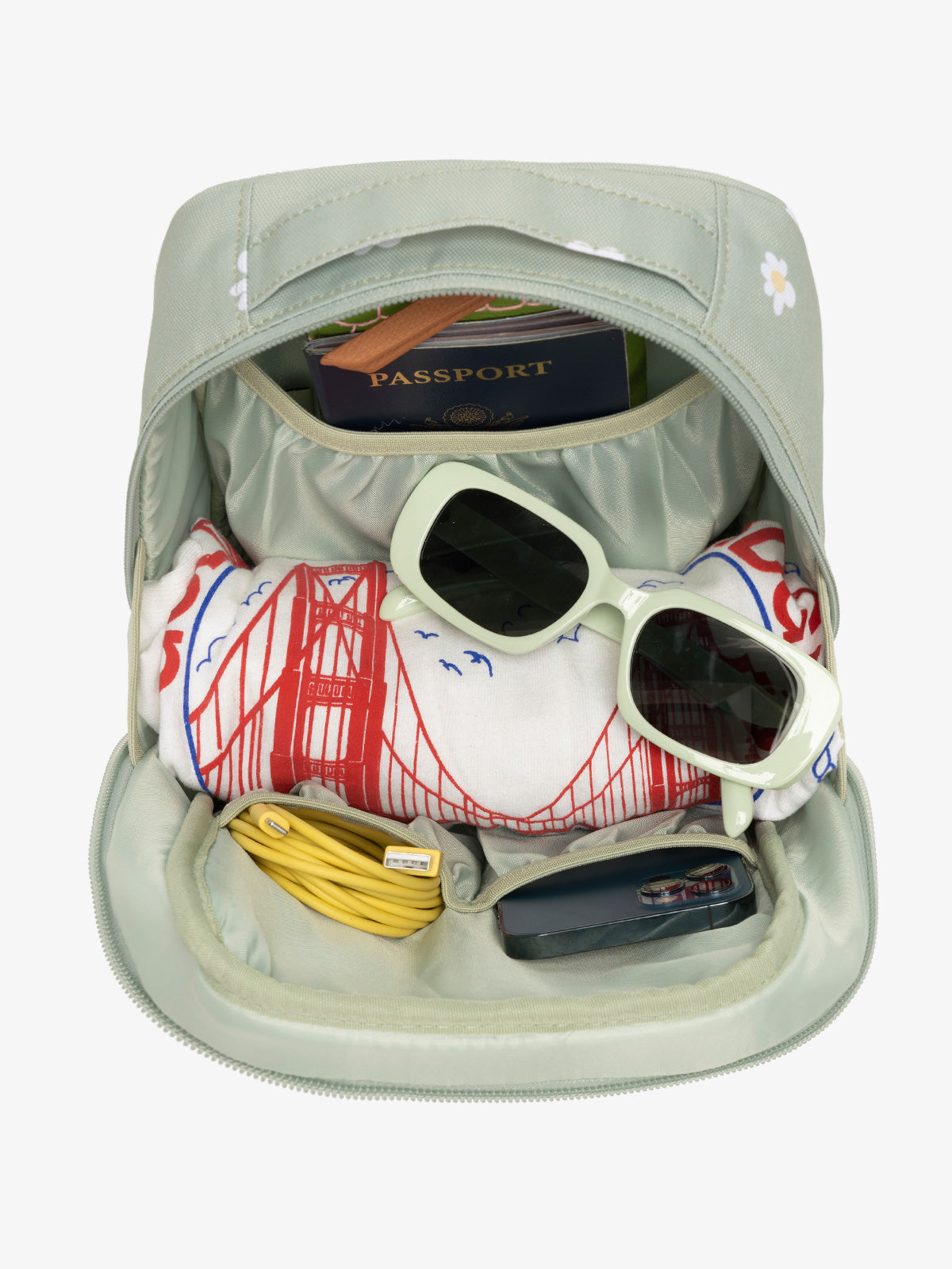 Interior view of daisy CALPAK The Everything Cube with notebook and passport in large slip pocket, cords and phone in front slip pockets, and sunglasses and t-shirt in main compartment; ACE2401-DAISY