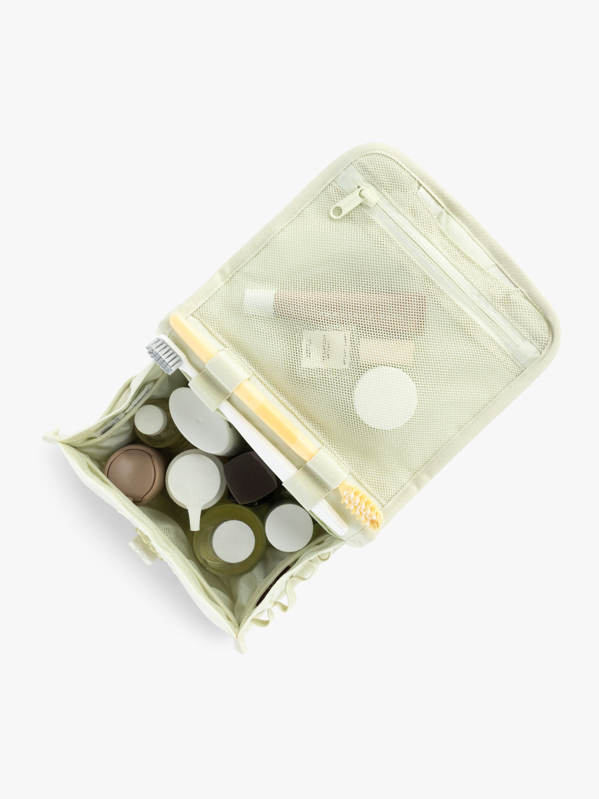 Toiletry items in the CALPAK Terra Hanging Toiletry Bag in light green Celadon with front buckle; THY2201-CELADON