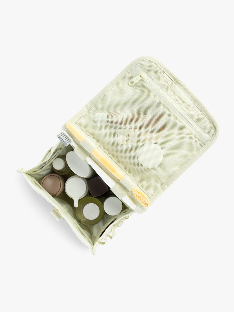 Toiletry items in the CALPAK Terra Hanging Toiletry Bag in light green Celadon with front buckle