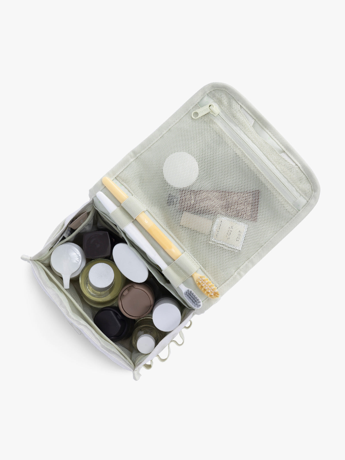 Toiletry items in CALPAK Terra Hanging Toiletry Bag in shiny white Moonbeam with front buckle; THY2201-MOONBEAM
