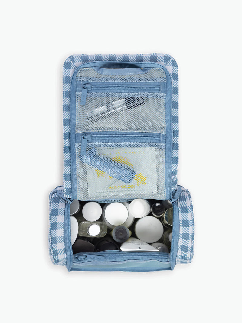 Toiletries in the CALPAK Luka Hanging Toiletry Bag in white and blue gingham print in French Blue Gingham