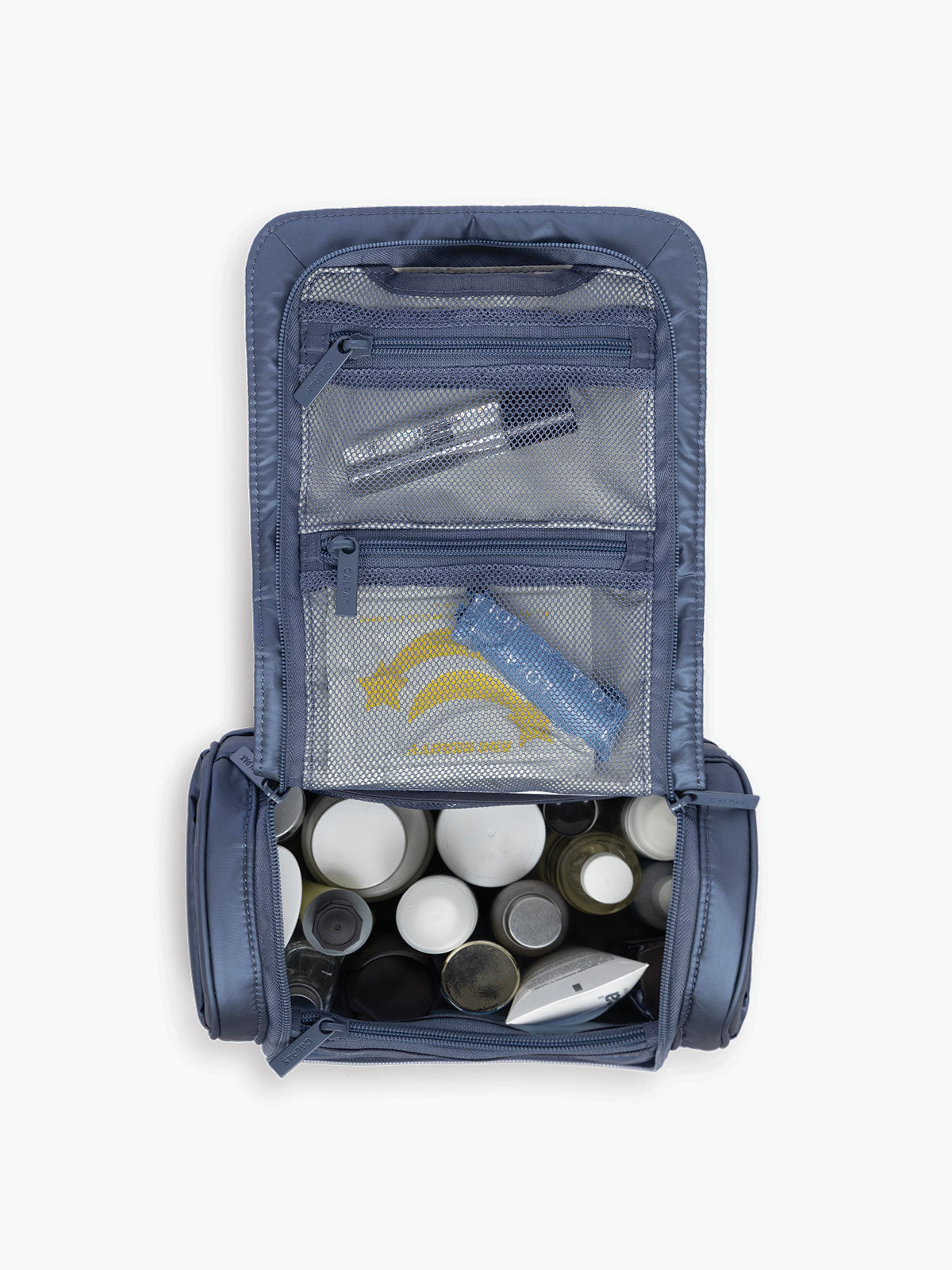 Toiletries inside the CALPAK Luka Hanging Toiletry Bag in metallic dark blue material in Metallic Indigo; TLH2301-METALLIC-INDIGO