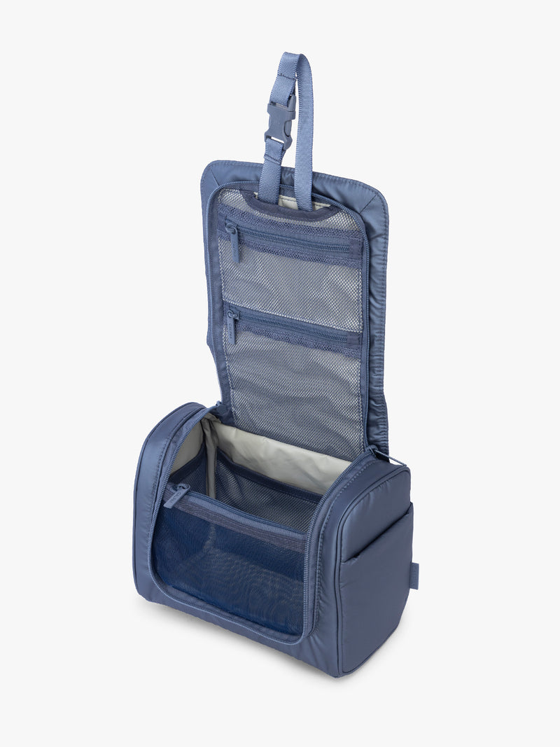 Opened view of CALPAK Luka Hanging Toiletry Bag in metallic dark blue material in Metallic Indigo