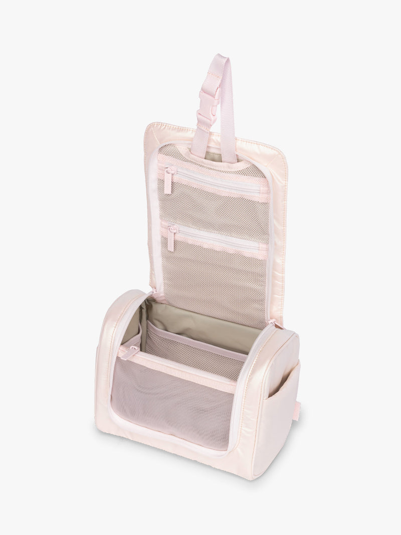 Opened CALPAK Luka Hanging Toiletry Bag in light pink shiny Pearlescent