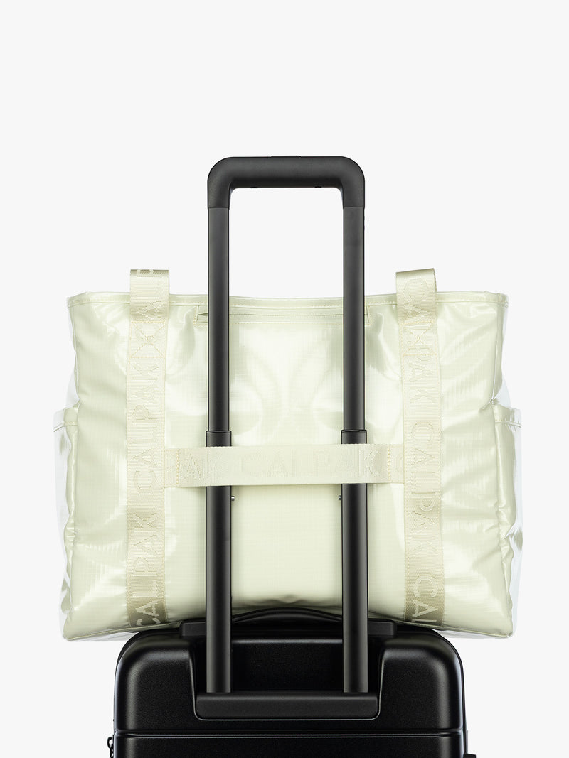 Luggage trolley strap of the CALPAK Terra 35L Tote Bag with multiple pockets and shoulder straps in shiny light green Celadon on a white background