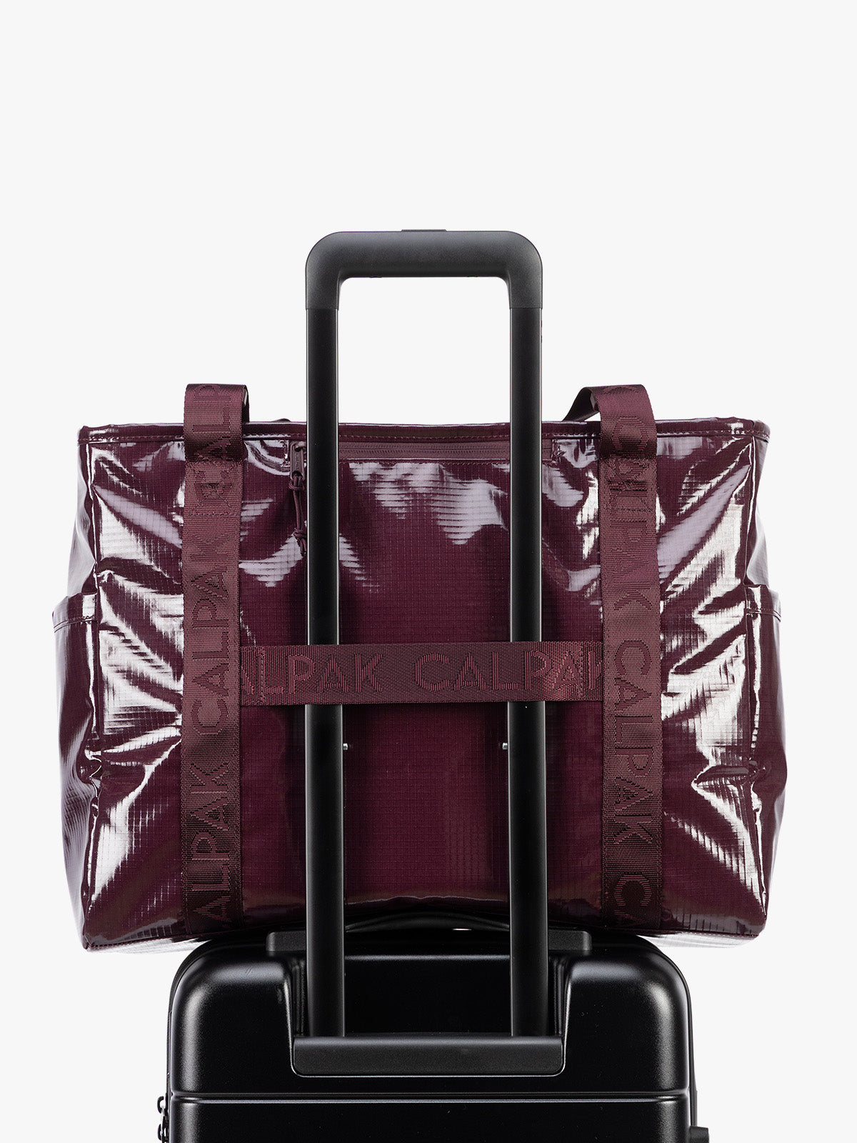 Back trolley sleeve of CALPAK Terra 35L Tote Bag with zippers in dark red Dark Cherry on a white background; TTO2401-DARK-CHERRY