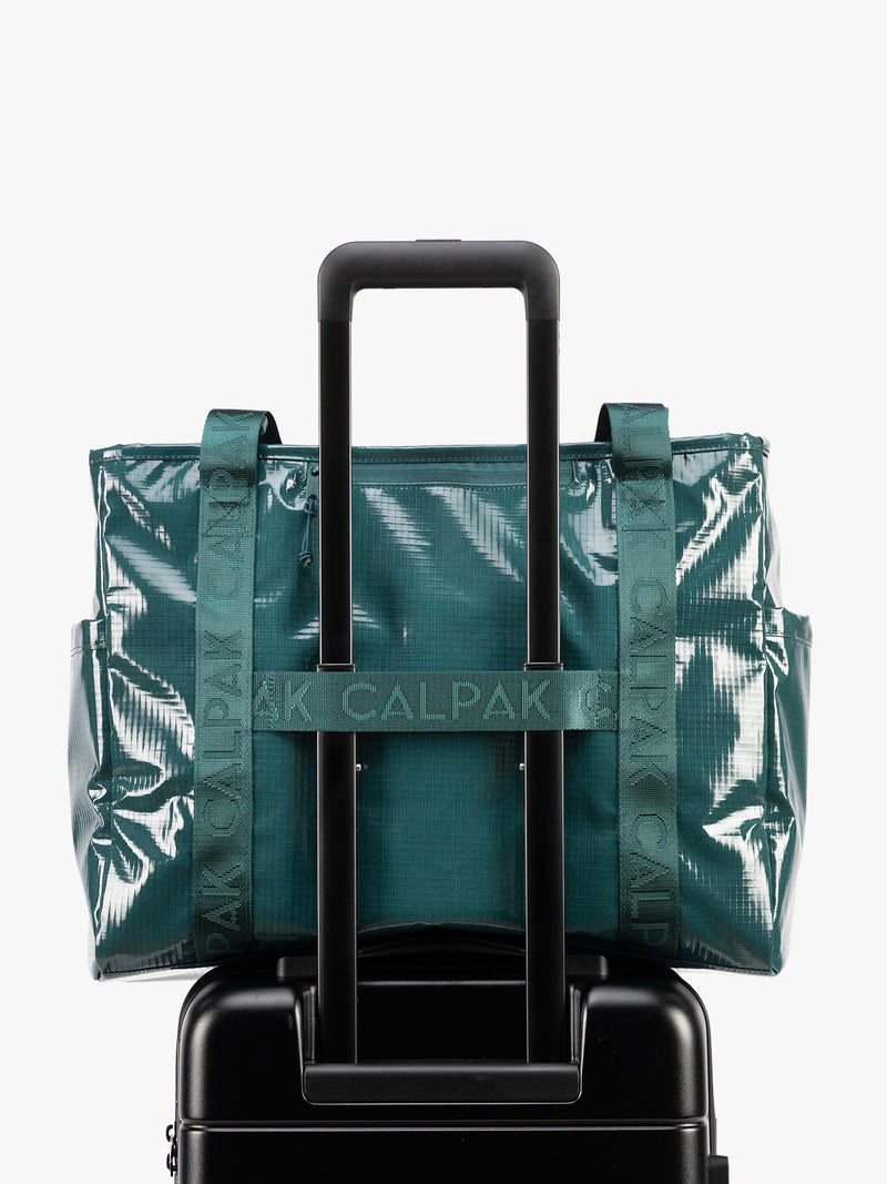Back trolley sleeve of CALPAK Terra 35L Tote Bag with zippers in blue green Kale on a white background