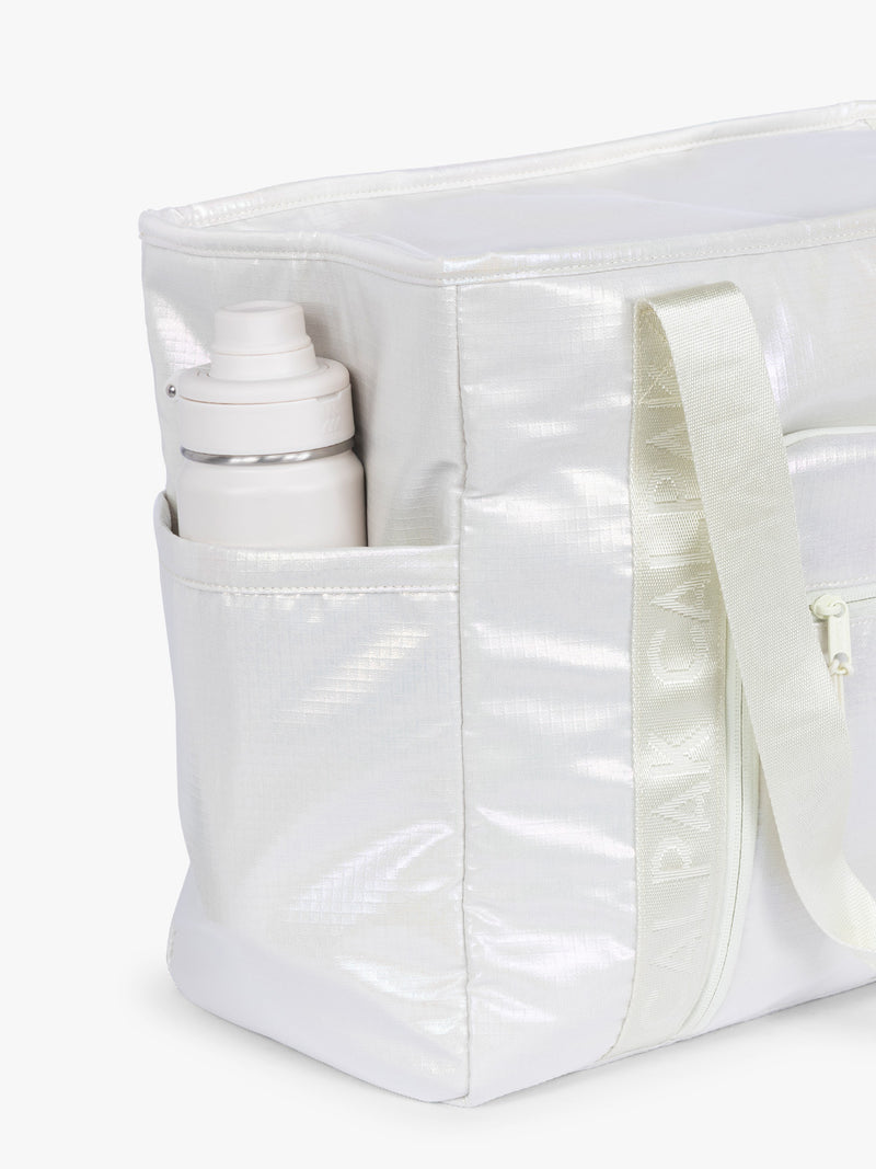 Side water bottle holder of CALPAK Terra 35L Tote Bag with multiple pockets and shoulder straps in shiny white Moonbeam on a white background