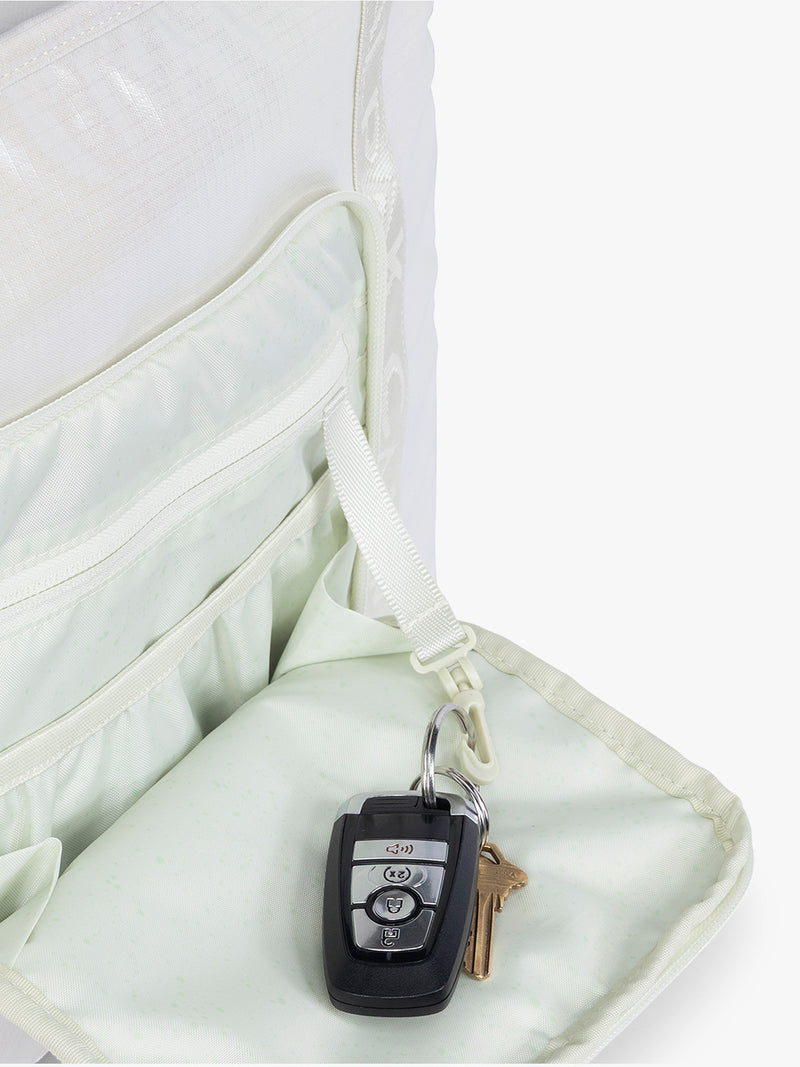 Key leash in the front pocket of the CALPAK Terra 35L Tote Bag with multiple pockets and shoulder straps in shiny white Moonbeam on a white background