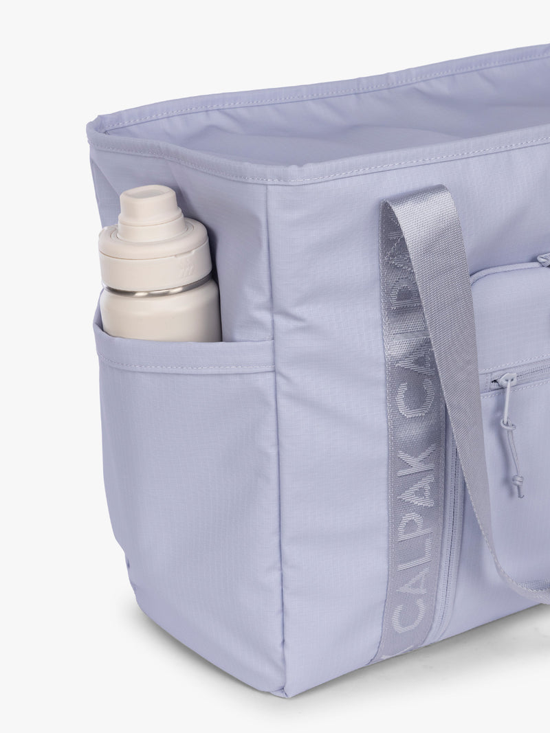 Side water bottle pocket of the CALPAK Terra 35L Tote Bag with multiple pockets and shoulder straps in shiny light lavender Sea Glass on a white background